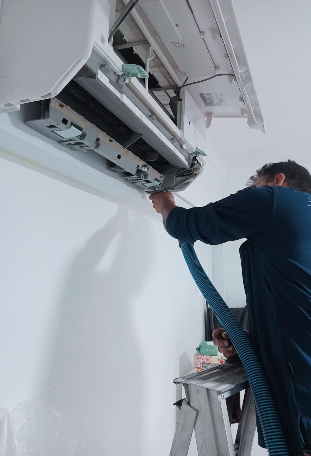 Technician performing general servicing on an indoor aircon unit